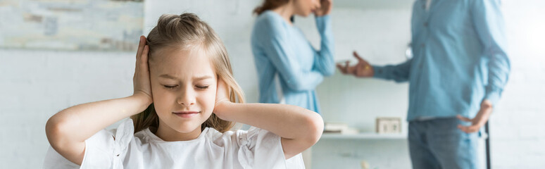 panoramic shot of kid with closed eyes covering ears near parents at home