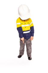 Young blond caucasian boy pointing down at something role playing as a construction worker supervisor in a yellow and blue hi-viz shirt, boots, without the white hard hat, hammer and tape measure.