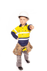 Young blond caucasian boy pointing out with a fierce look role playing as a construction worker supervisor in a yellow and blue hi-viz shirt, boots, white hard hat, tool belt, and tape measure.