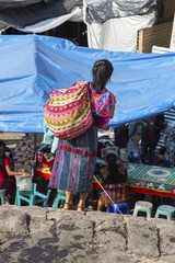 Ethnic Guatemalan Woman with shoulder bag carrying merchandise for sale walking on Thursday Chichicastenango Market day in Guatemala