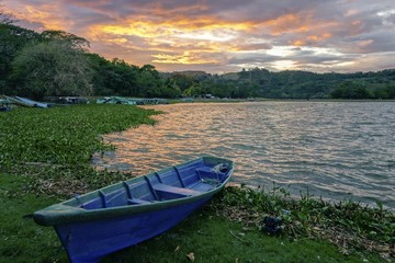 Blue Fishing Boat on Shore of Beautiful Lake Suchitlan and Dramatic Sunset Sky near Town of Suchitoto in El Salvador