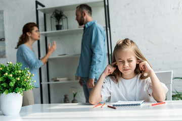 Fototapeta premium selective focus of girl with closed eyes covering ears near quarreling parents