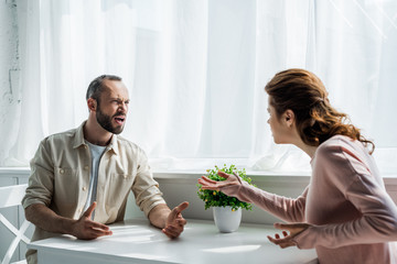 selective focus of angry man gesturing and looking at woman