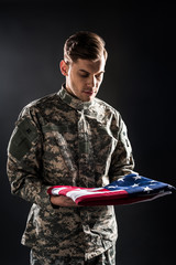 man in military uniform looking at american flag on black