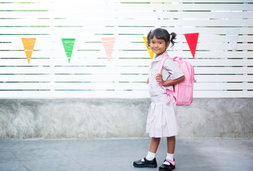 A female student carrying a school bag to travel to school on the new school term.