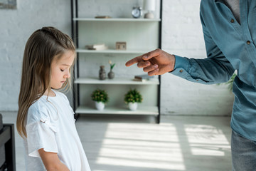 cropped view of man pointing with finger at adorable daughter at home