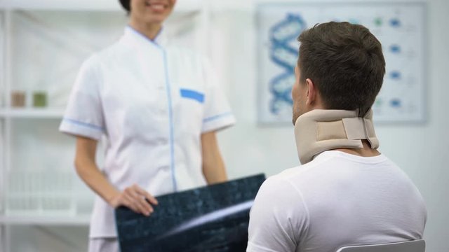 Radiologist informing patient in foam cervical collar good examination result