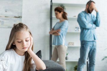selective focus of sad kid near quarreling parents at home