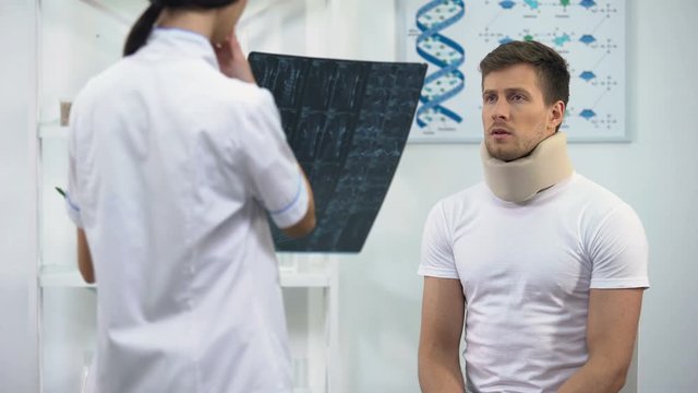 Female surgeon informing patient in foam cervical collar about bad x-ray result