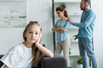 Fototapeta premium selective focus of frustrated kid looking at camera near quarreling parents at home
