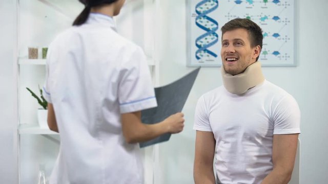 Doctor informing patient in foam cervical collar about good x-ray result, rehab