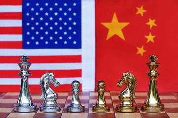 Chess board game pieces on USA and China flag background, trade war tension situation concept