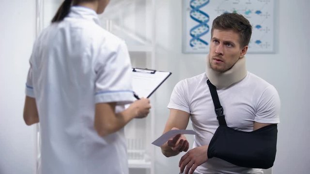 Doctor giving bill to patient in arm sling and foam collar, expensive treatment