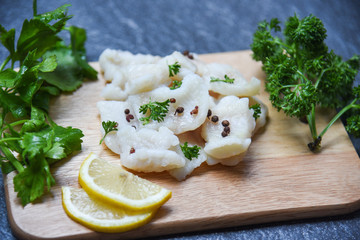 Cooked fish fillet piece with lemon and spices on wooden cutting board background - pangasius dolly fish meat