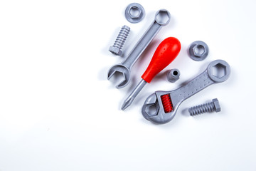 Kids construction toys tools: colorful screwdrivers, screws and nuts on wooden background. Top view. Flat lay. Copy space for text