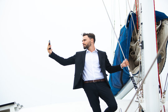 Luxury business man  taking selfie from phone on a sailing boat. Concept business travel