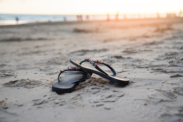 Fototapeta na wymiar flip flops on beach with sandy beach sunset and ocean sea