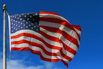 Slight Motion blur American flag against a blue sky with clouds