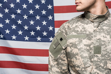 cropped view of man in military uniform near flag of america