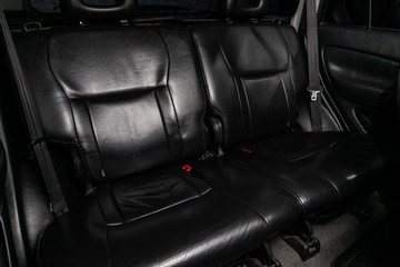 Naklejka premium Сlose-up of the car black interior: black leather rear seats and seat belts .