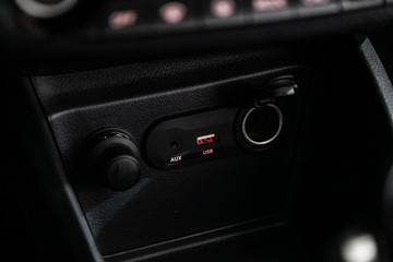 Сlose-up of the car  black interior:  power outlet 12V, USB, AUX and other buttons.