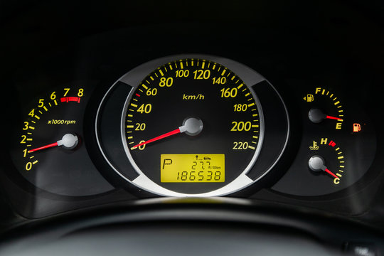Сlose-up of the car  black interior:  dashboard, speedometer and tachometer with green backlight and other buttons.