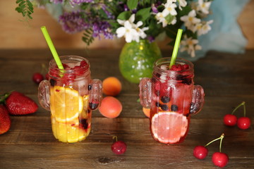 smoothies in glass bottles with straws of fresh fruit and berries on a rustic wooden table decorated with flowers and fruits. Detox, diet, healthy nutrition concept.