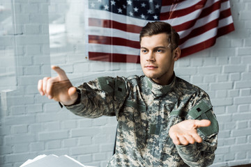 handsome man in camouflage uniform pointing with finger in office