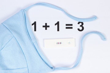 Pregnancy test with positive result and cap for newborn, concept of expecting for baby
