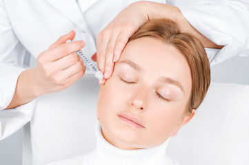 Obraz na płótnie Canvas Woman is getting injection. Anti-aging treatment and face lift. Facial skin lifting injection to woman's face.