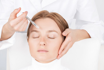 Obraz na płótnie Canvas Woman is getting injection. Anti-aging treatment and face lift. Facial skin lifting injection to woman's face.