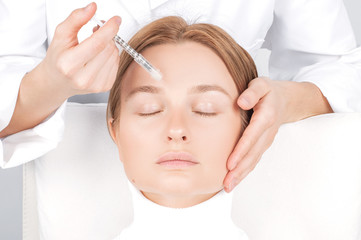 Woman is getting injection. Anti-aging treatment and face lift. Facial skin lifting injection to woman's face.