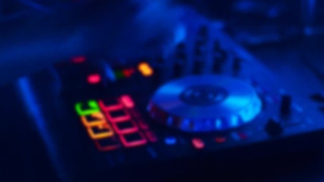 colorful blurred abstract background with flashing bokeh lights and silhouettes of Hands DJ are playing track controls on dj's deck, camera is breathing