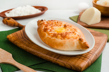 Ajar-style khachapuri with cottage cheese and egg yolk. Home cooking food photography in warm tones.
