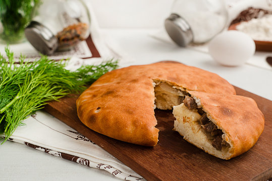 Savory traditional Russian pie with meat and dill. Showing ingredients. Home cooking food photography in warm tones.