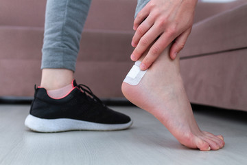 Female heel with bactericidal medical adhesive plaster close up. First band aid