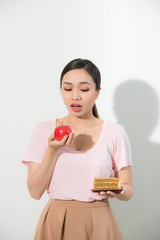 Young beautiful girl with apple and cake in her hands on a white background. Healthy food concept