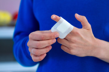 Woman using adhesive plaster for injured finger. First aid for cuts and wounds
