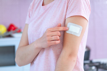 Woman using a medical bactericidal adhesive plaster on arm after vaccination, injection vaccine or medicine. First aid for cuts and wounds