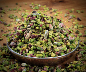 cracked pistachios in a bowl on wooden table