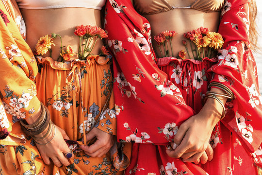 close up of two beautiful stylish boho model in colorful costumes with flowers