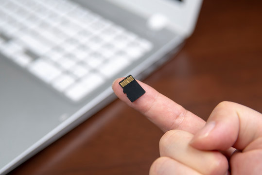Human hand plugging in an Micro SD media card into the personal laptop computer.