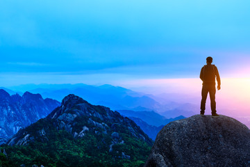 Young happy backpacker on top of a mountain enjoying valley view