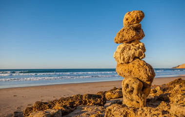 Fototapeta na wymiar Stack of five small rocks balancing on a sunny beach