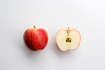 Whole and cross section of fresh gala apples, showing pips and core, isolated on white.