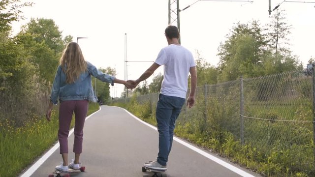 Couple skateboarding together and holding hands