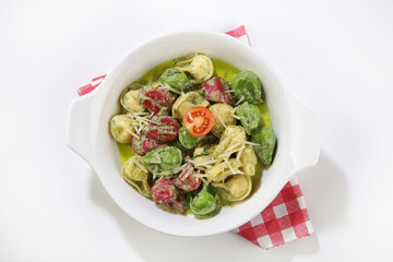 basil sauced pasta with vegetables top view isolated background