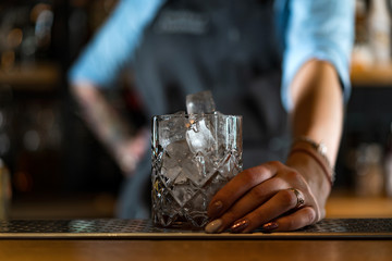 Fototapeta na wymiar ice cubes in a wine glass in a female hand in a bar