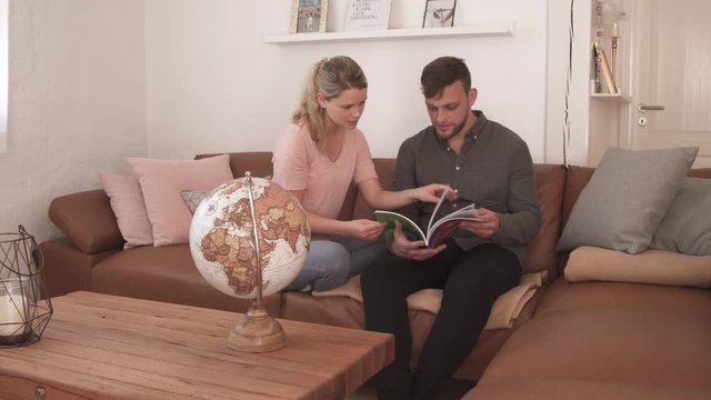 Couple reading magazine on couch at home