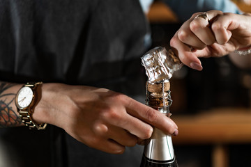 the girl opens the champagne, removes the foil